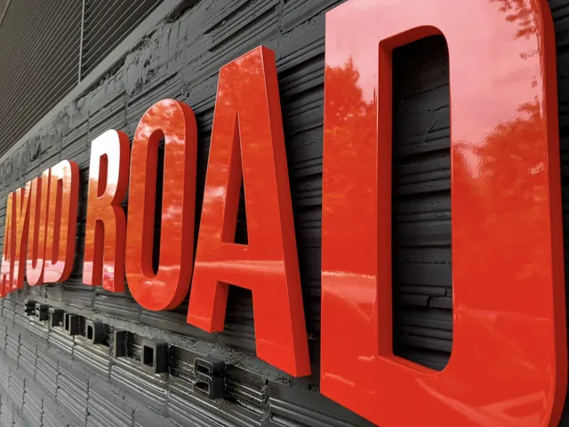 Rótulo de Ayud Road Estudios con letras rojas en relieve en la fachada de la academia